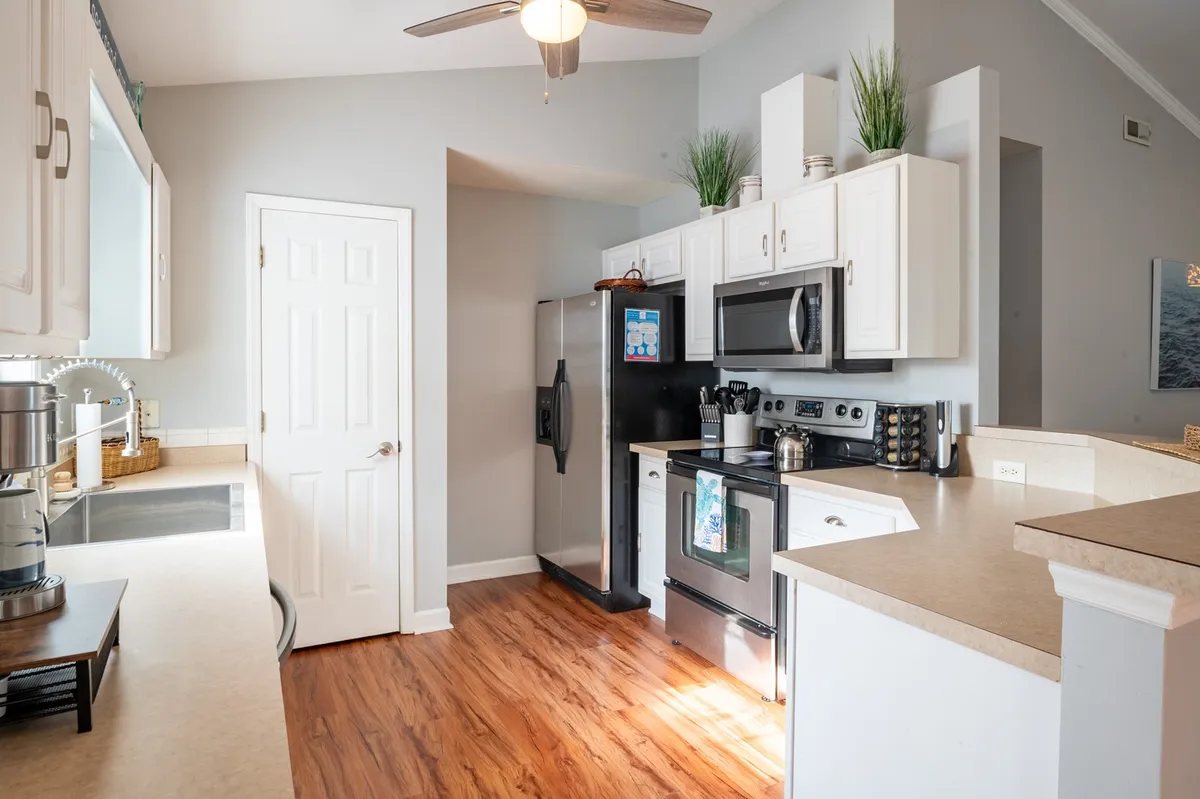 A second kitchen featuring abundant countertop space, modern appliances, a kitchen island, and warm wooden flooring. The setup is inviting and practical, supporting collaborative meal prep and family gatherings.