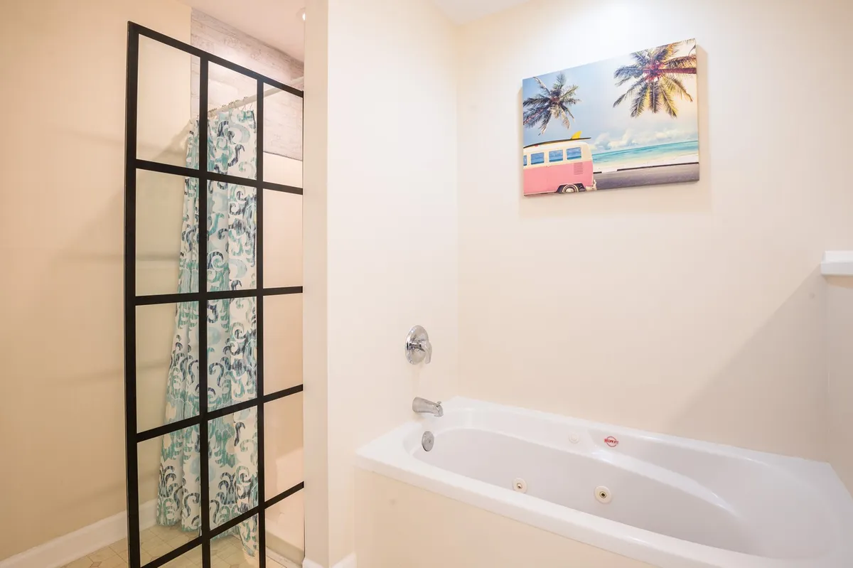 A tranquil bathroom scene featuring a bathtub and shower area, adorned with calming wall art. The space is designed for rejuvenation, inviting guests to relax and unwind after a day of adventure.