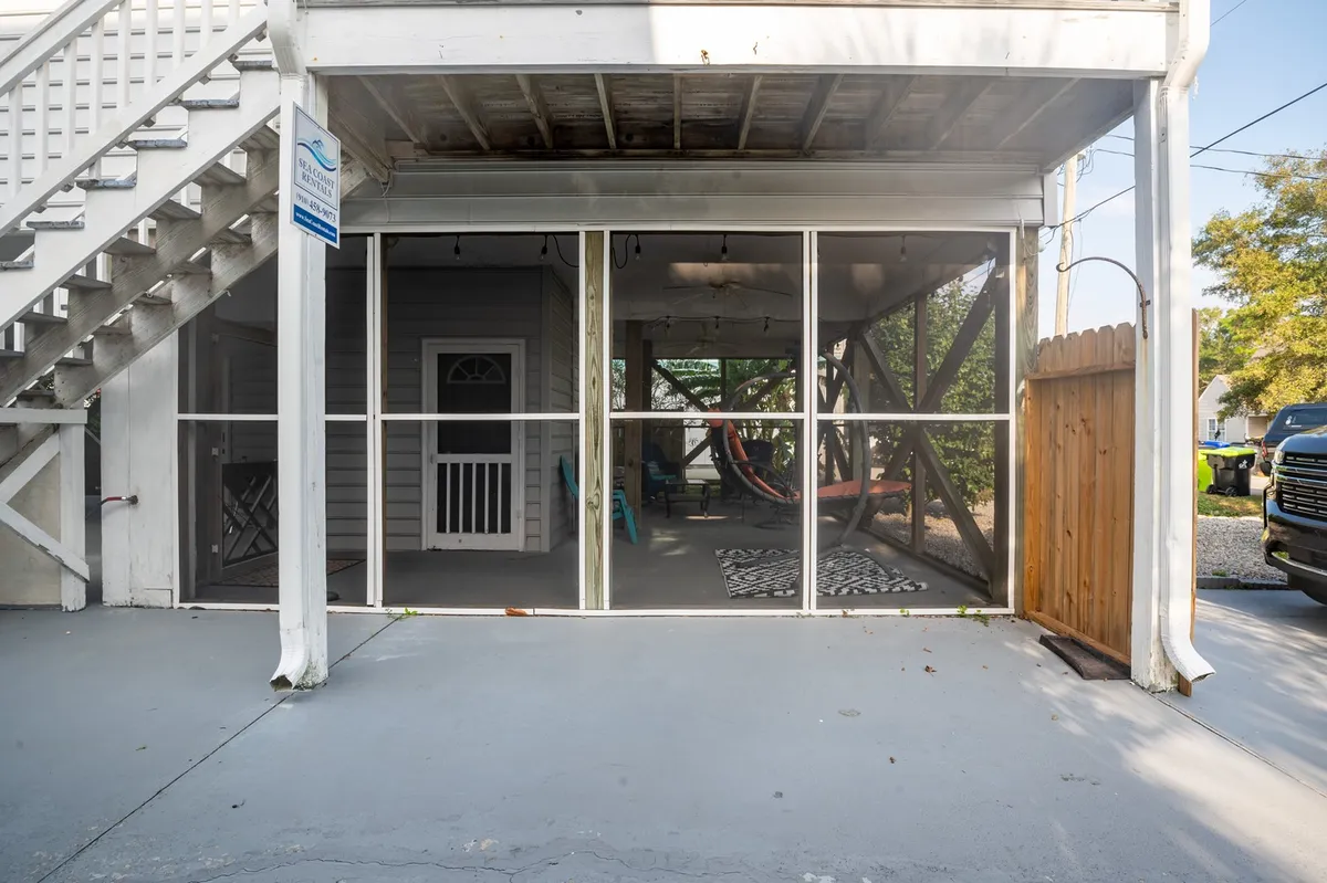 A bright, screened-in porch area featuring a hammock, colorful chairs, and a decorative rug. The space is filled with natural light, offering a relaxed yet lively atmosphere perfect for group gatherings. The view hints at the outdoors, suggesting a seamless transition between indoor comfort and fresh air.