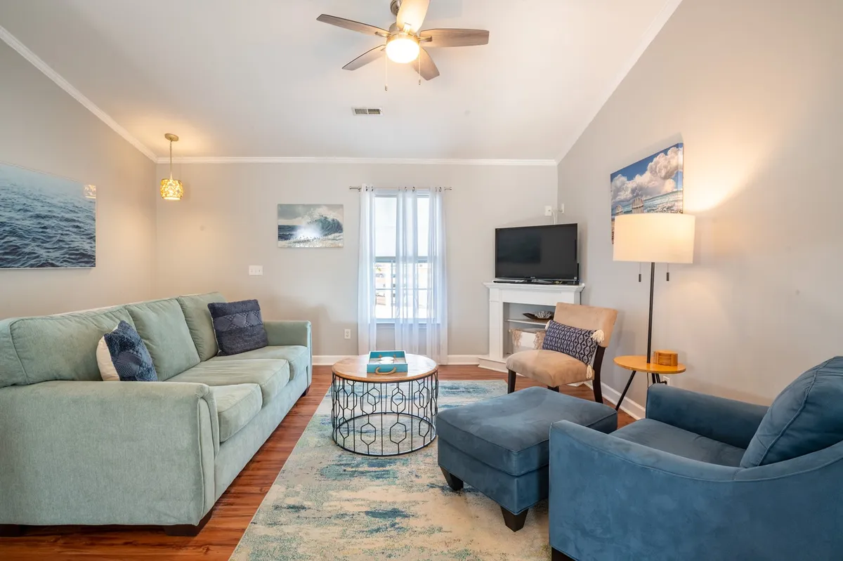 A comfortable living space with a sofa, coffee table, TV, armchair, and a window letting in soft natural light. The arrangement is ideal for both socializing and quiet relaxation, evoking a sense of warmth and togetherness.