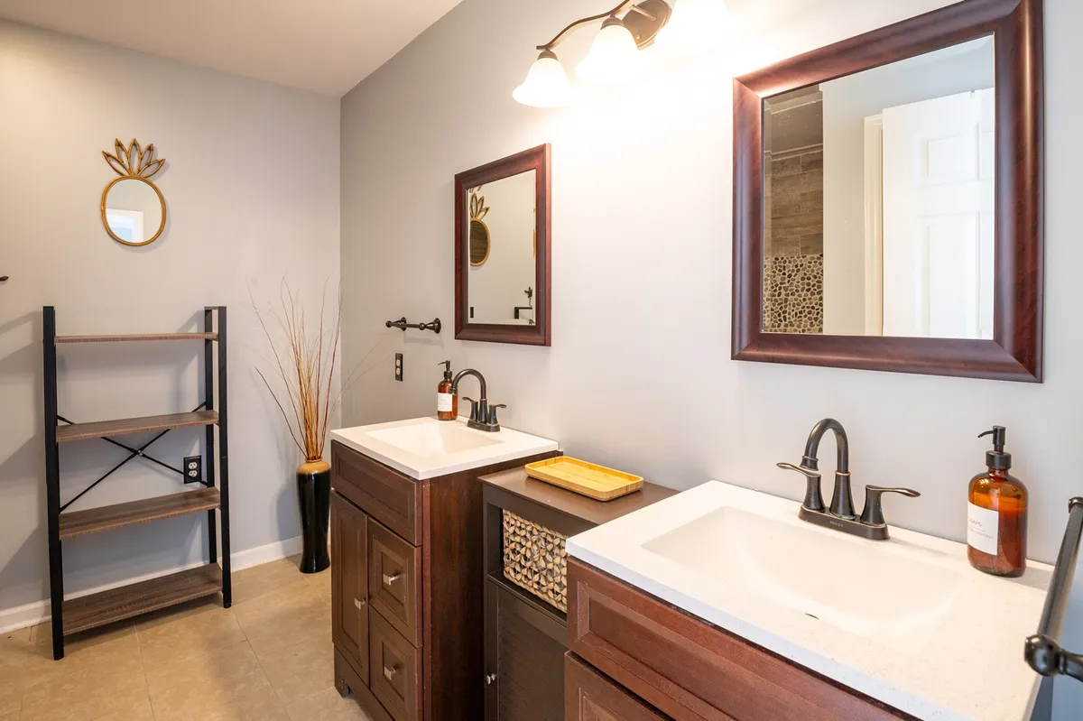 A serene bathroom with a spacious vanity featuring dual sinks, large mirrors, ample shelving, and decorative items. The room has a spa-like ambiance, emphasizing comfort and convenience for morning and evening routines.
