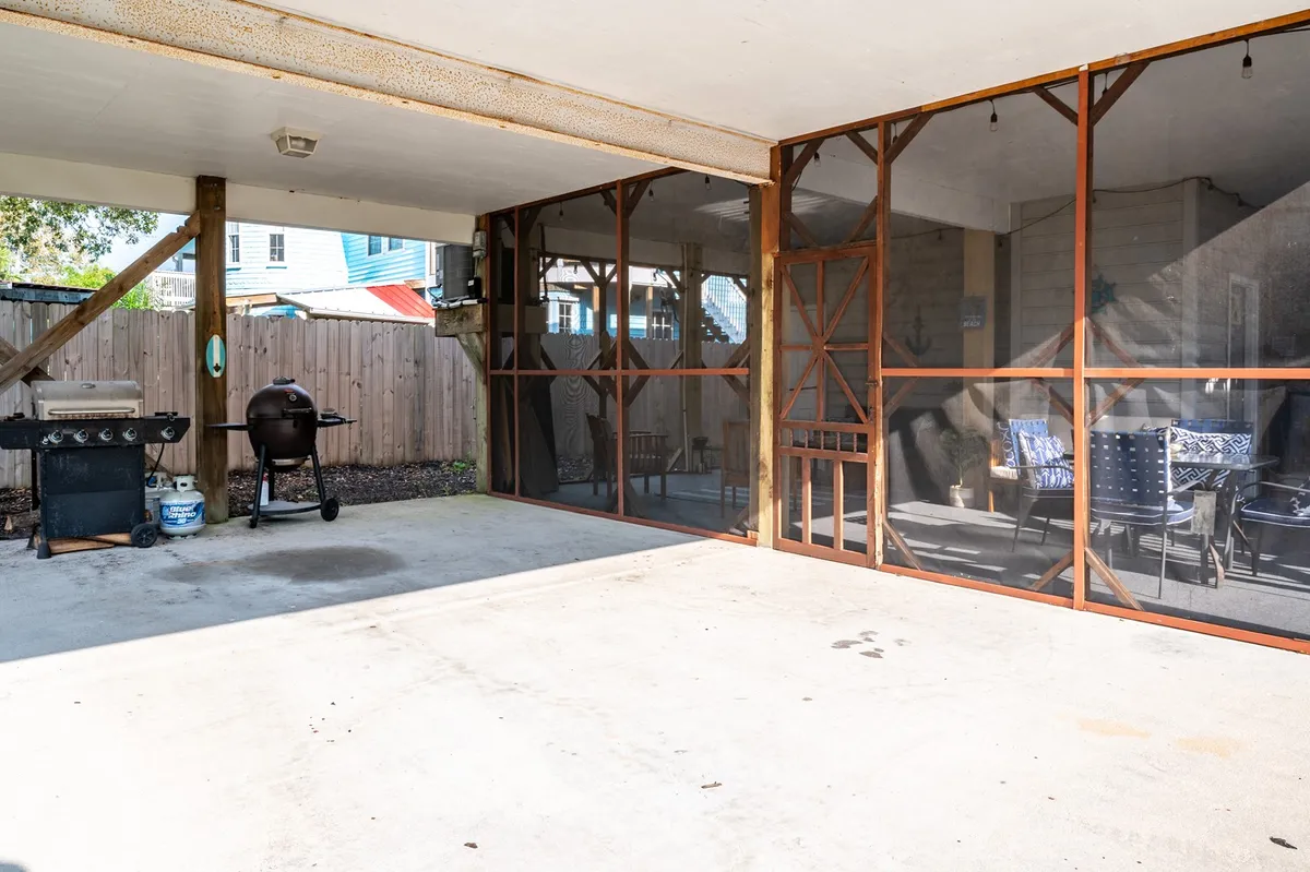 A welcoming area featuring a grill, ample seating, and screened windows, designed for barbecuing, relaxing, and entertaining guests. The space feels both open and intimate, set up for group feasts or quiet mornings alike.