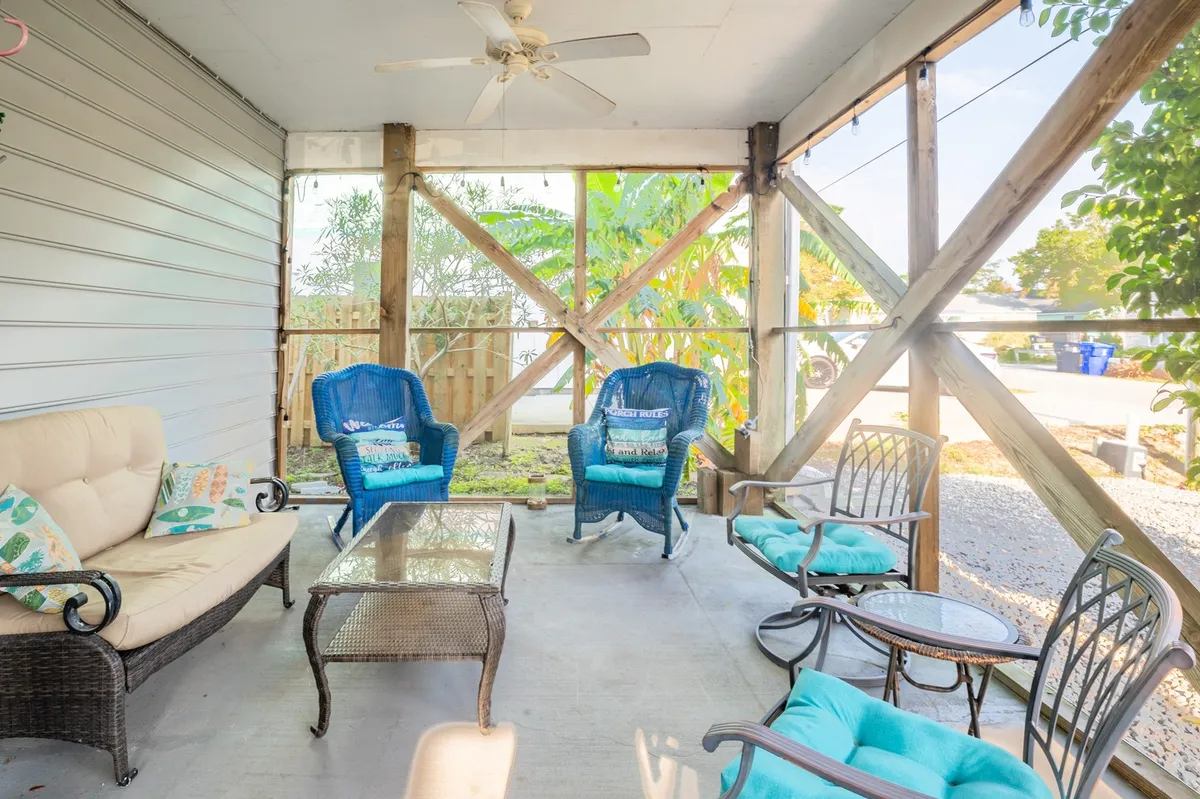 A sunlit lounge with comfortable seating, decorative pillows, a coffee table, and views of exterior greenery. The space feels open and welcoming, with ample light pouring in, subtly connecting the indoors to the lush environment just outside.